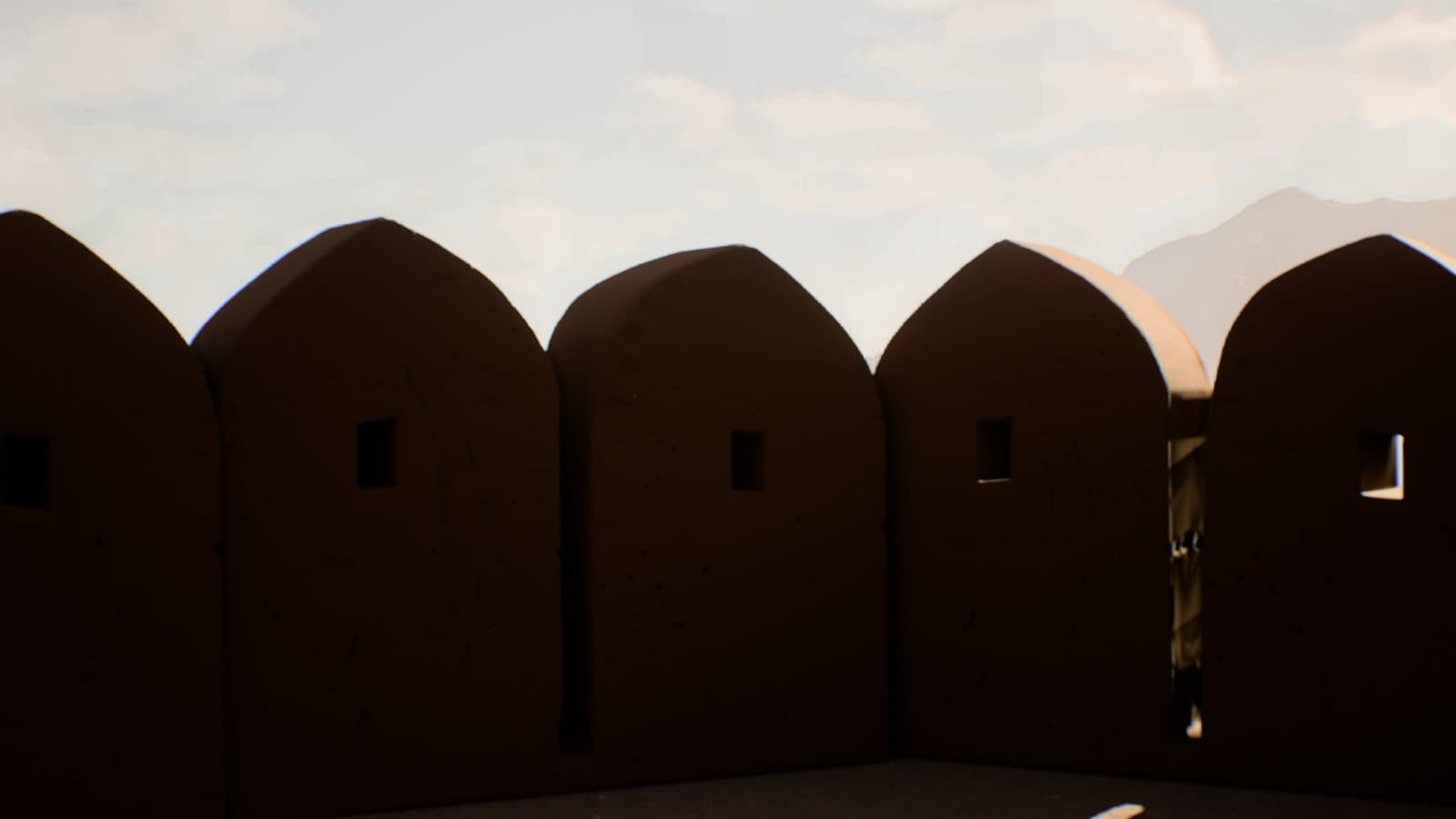 Merlons of a fort wall in shadow against a pale sky